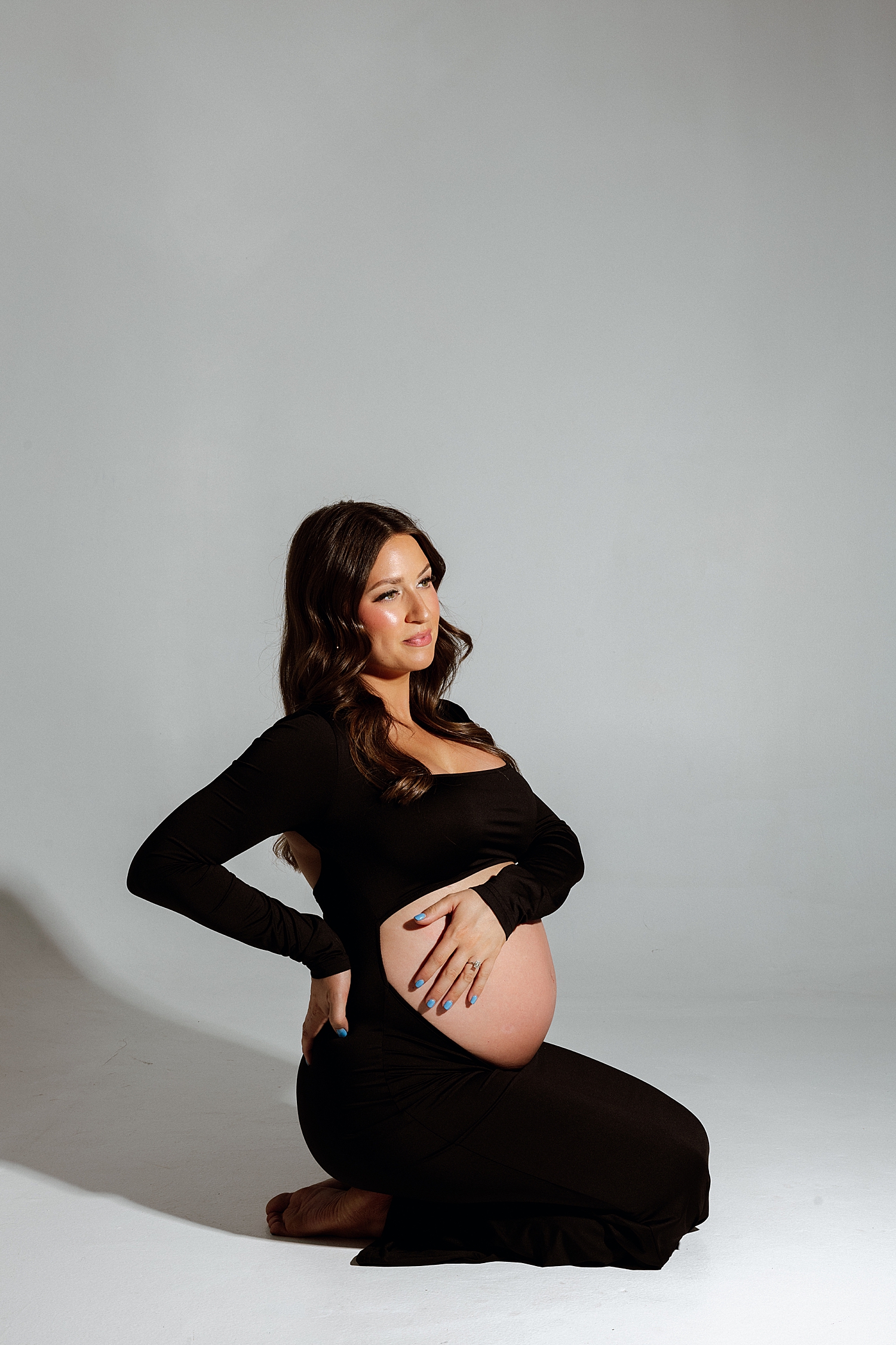 brunette expecting mama sitting in studio glamour lighting