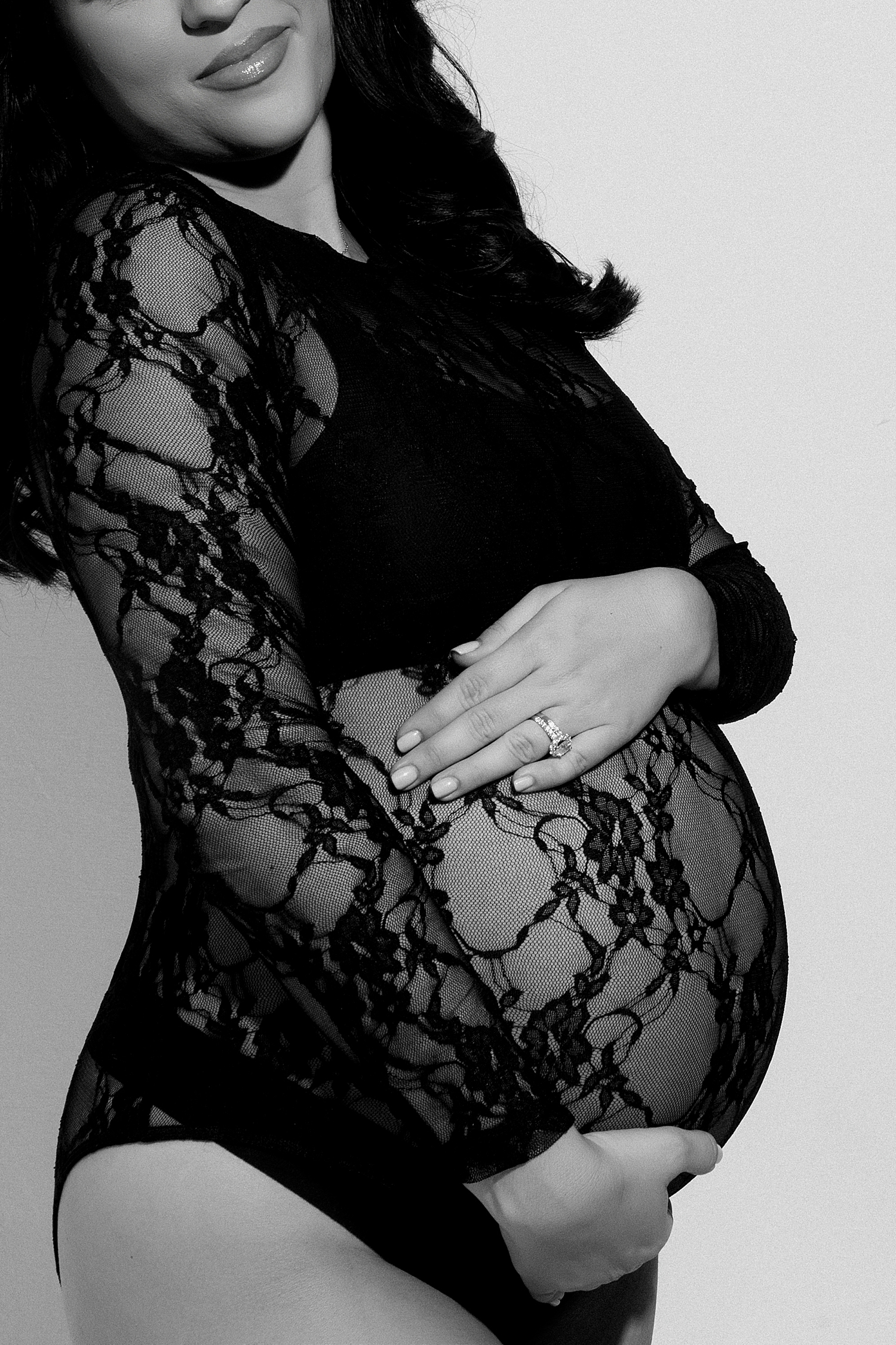 woman cradles her belly in black lace bodysuit for Studio Glam Mama Session